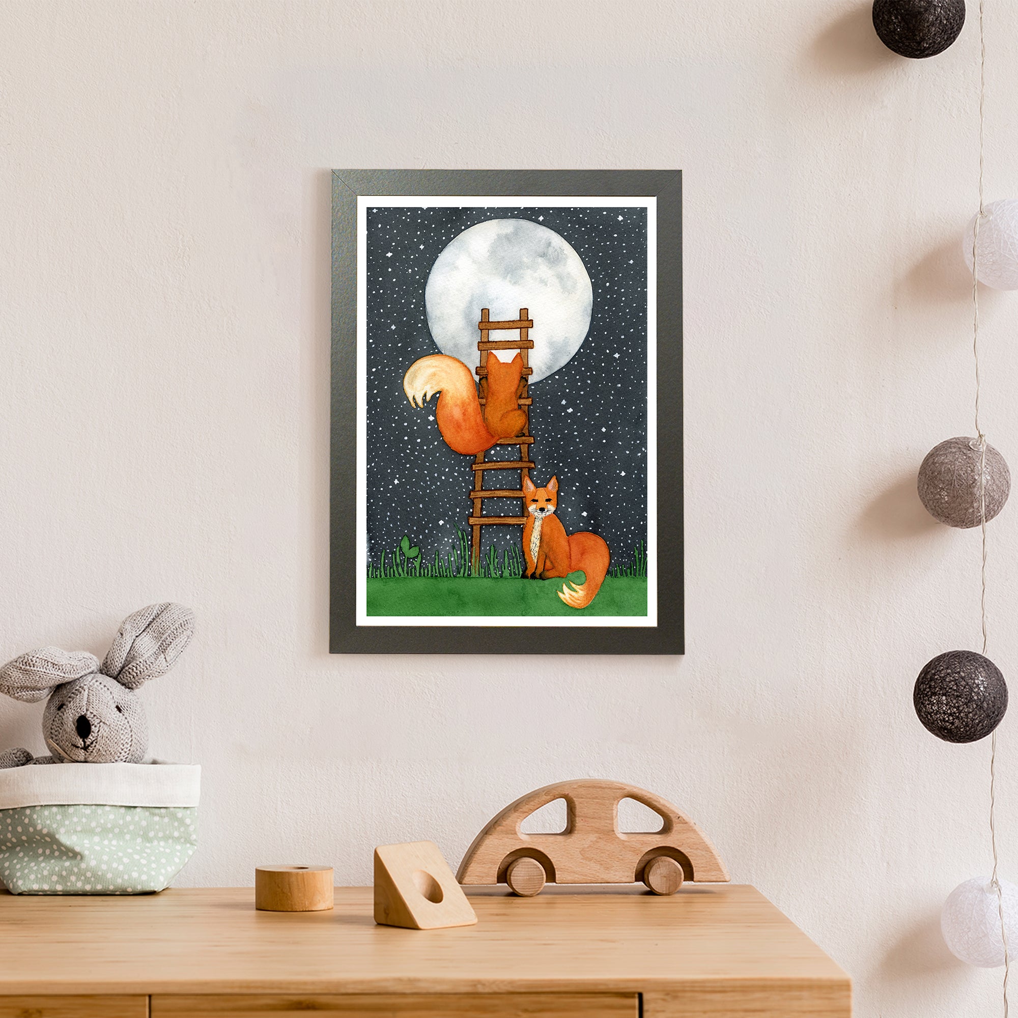 Two orange foxes try to reach a full moon by climbing a ladder in front of a starry night sky (print only)