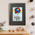 A grey elephant tied to a bunch of colourful balloons flies high among the clouds (A3 framed with black mount)