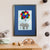 A grey elephant tied to a bunch of colourful balloons flies high among the clouds (A3 framed with blue mount)