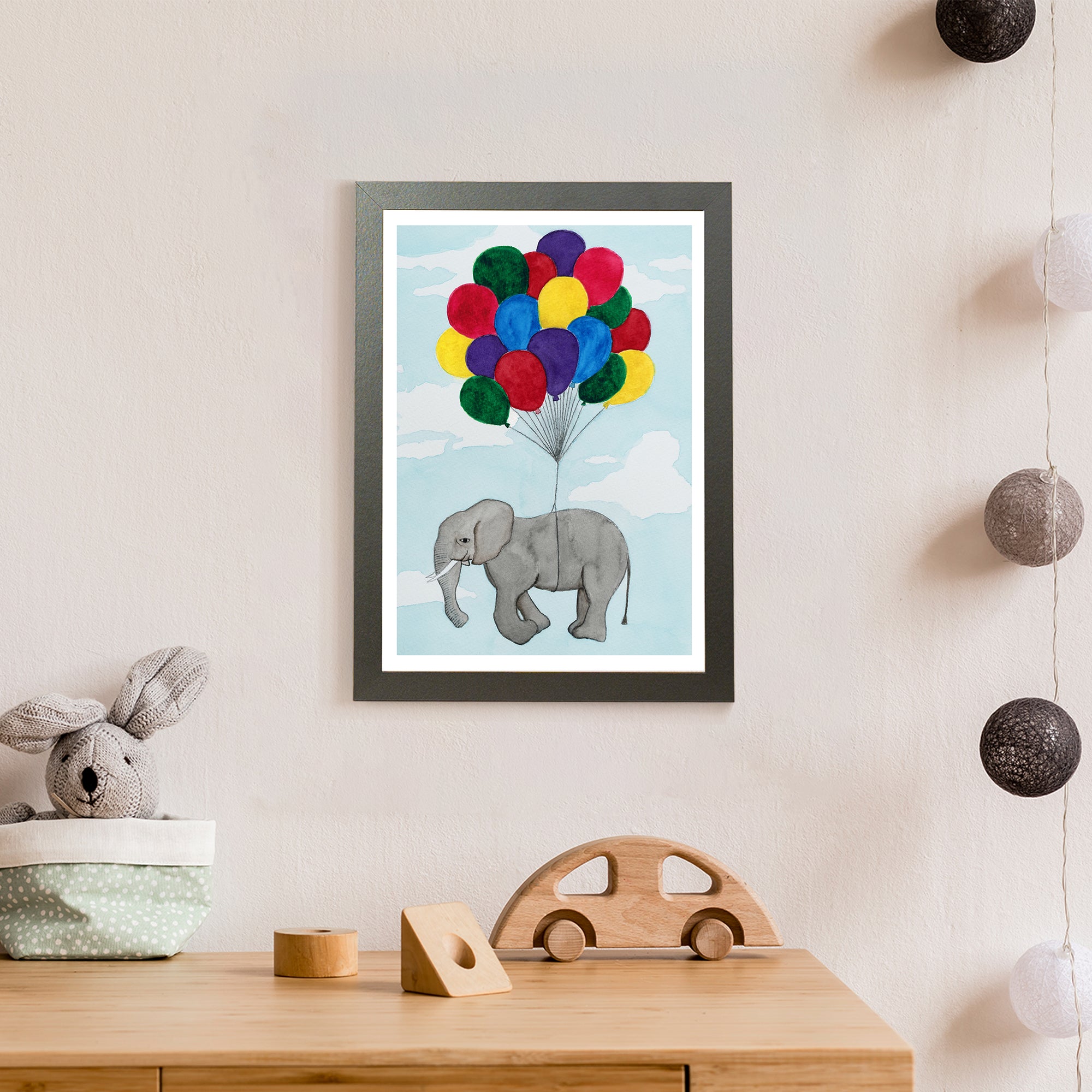 A grey elephant tied to a bunch of colourful balloons flies high among the clouds (print only)