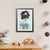 A grey elephant tied to a bunch of colourful balloons flies high among the clouds (A4 framed)
