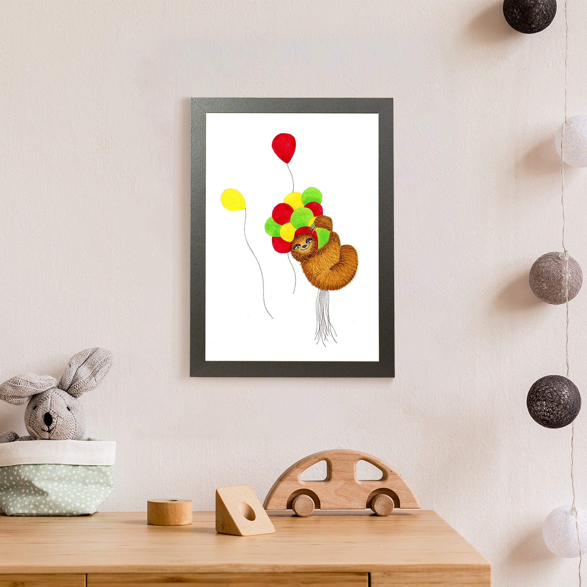 A furry brown sloth flies high while holding on to a bunch of red, yellow, and green balloons, though a couple of the balloons have escaped his grasp (print only)