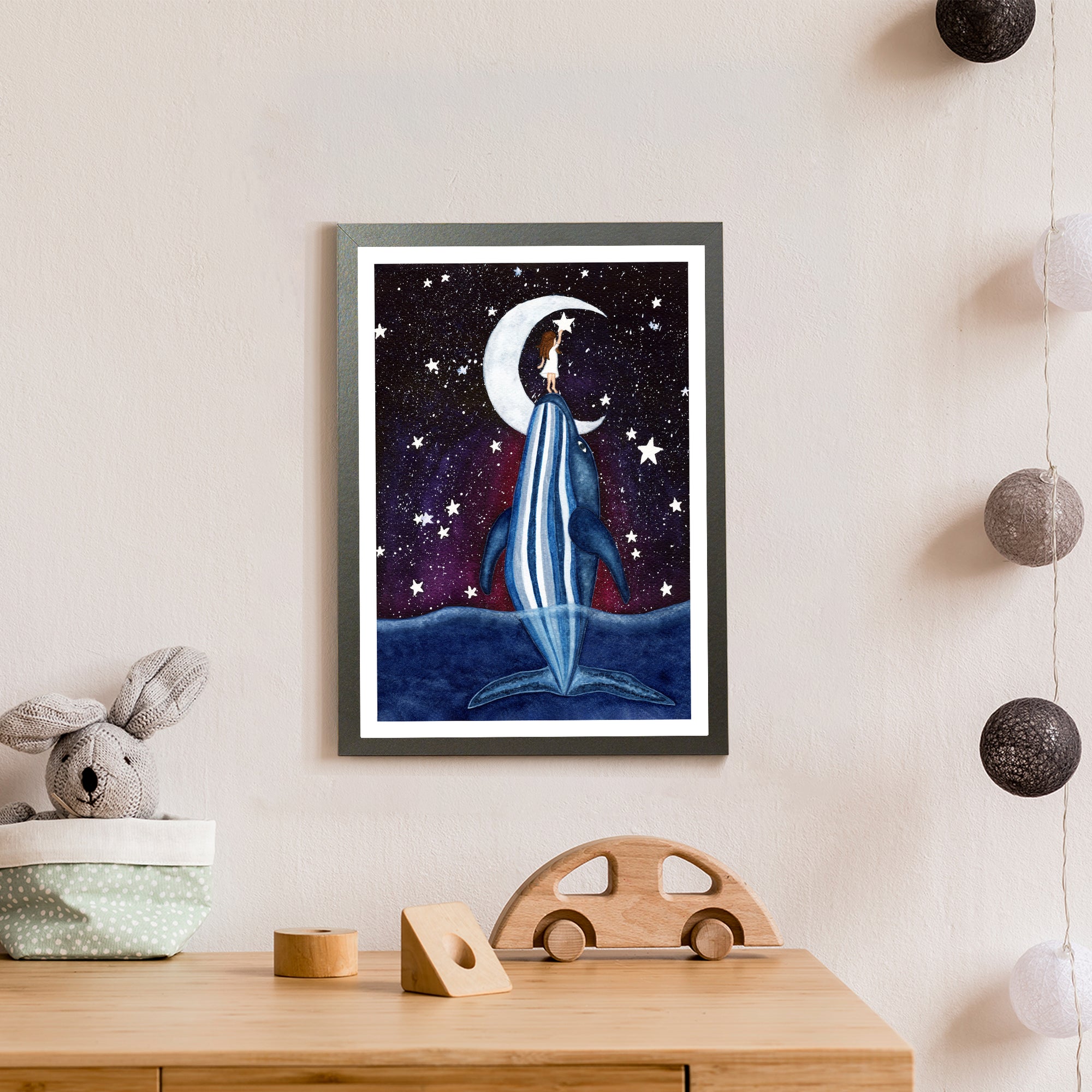 A white girl with brown hair is lifted up by a blue whale to grab a star out of a starry night sky in front of a crescent moon (print only)